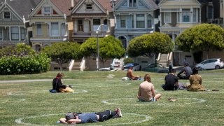 People sit on the grass in circles drawn to promote social distancing at Alamo Square in San Francisco, June 11, 2020.