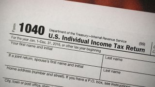 In this Dec. 22, 2017, file photo, a copy of an IRS 1040 tax form is seen at an H&R Block office in Miami, Florida.