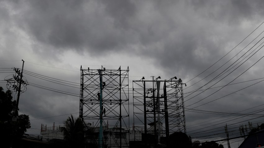 Dark clouds envelop the skies as workers fold a billboard to prepare for the coming of typhoon Vongfong in Manila, Philippines Thursday May, 14, 2020.