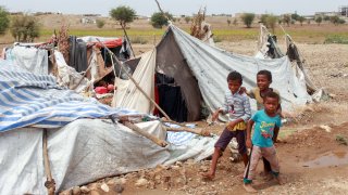 Yemeni children play next to tents damaged by torrential rain in a makeshift camp for the displaced in the northern Hajjah province, on April 19, 2020.