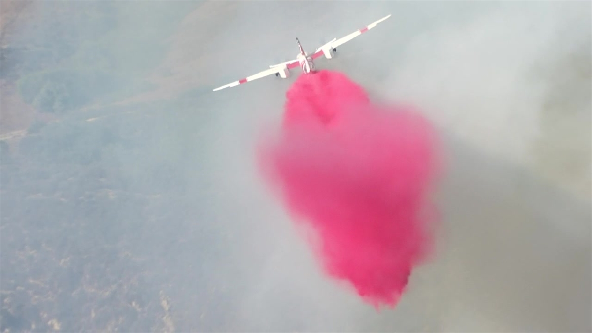 A firefighting airplane drops fire retardant on the Aliso fire in Orange County.