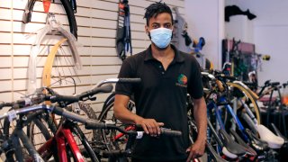 In this Wednesday, June 24, 2020, photograph, Noah Hicks, owner of Spokehouse Bikes in the Upham's Corner neighborhood of Boston, poses at his shop. Many from outside Boston have donated to and shopped at the store which was robbed and vandalized earlier in the month.