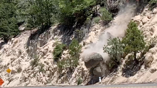 A boulder is removed from a hillside off Highway 18 in the San Bernardino Mountains