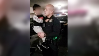 Armando Corona, in police uniform, holds one of his kids