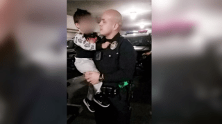 Armando Corona, in police uniform, holds one of his kids