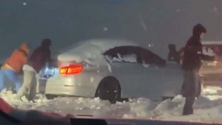 Drivers push car stuck in snow on freeway