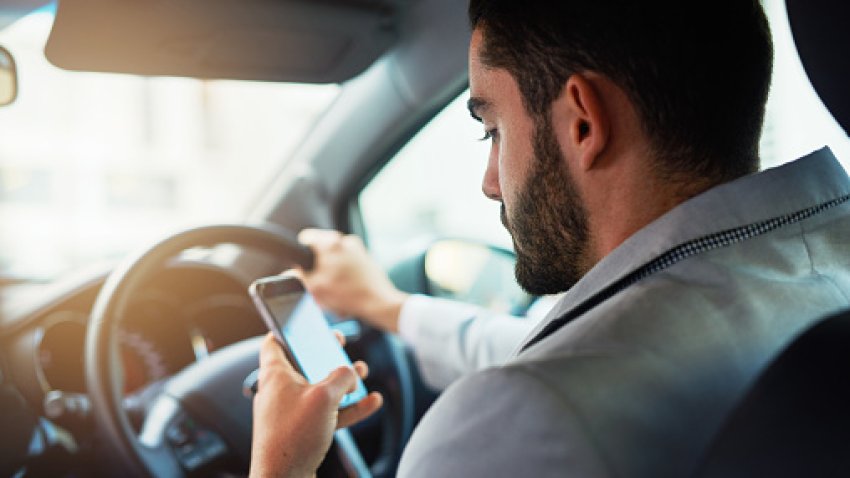 Cropped shot of a man using his phone while driving