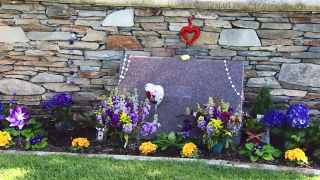 A grave with purple and gold flowers