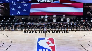 Members of the New Orleans Pelicans and Utah Jazz kneel together around the Black Lives Matter logo on the court during the national anthem before the start of an NBA basketball game Thursday, July 30, 2020, in Lake Buena Vista, Fla.