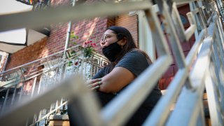 Natalia Afonso, 27, an international student from Brazil at Brooklyn College, sits on a stoop outside her home during an interview, Thursday, July 9, 2020, in New York. Afonso, who is studying teaching education and finished her first semester this spring, said she has lived in the U.S. for 7 years and "I don't see myself moving back to Brazil at this point.