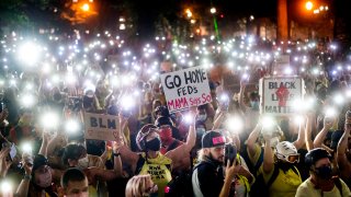 Hundreds of Black Lives Matter protesters hold their phones aloft