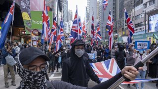 Demonstrators wave the British Union flag, also known as a Union Jack, as they march during a protest on Hennessy Road in the Causeway Bay district of Hong Kong, China, on Wednesday, Jan. 1, 2020.