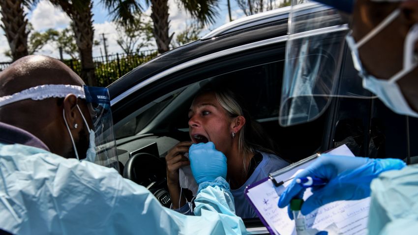 A medical personnel member takes samples on a woman at a "drive-thru" coronavirus testing lab set up by a local community center in West Palm Beach