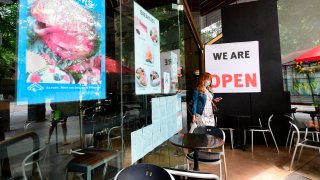 A woman steps out of a restaurant.