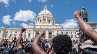Supporters raise their fists while standing at the Minnesota State Capitol.