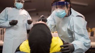 Health care workers use a nasal swab to test a person for COVID-19 at a pop up testing site in Pembroke Park, Fla., on July 22, 2020