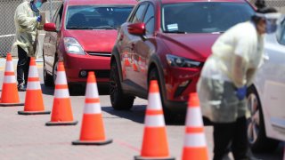 In this July 31, 2020, file photo, vehicles line up at a drive-in COVID-19 testing center at Charles R. Drew University of Medicine and Science in South Los Angeles amid the coronavirus pandemic in Los Angeles, California.