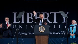 President of Liberty University Jerry Falwell (L) and others clap as US President Donald Trump prepares to speak during Liberty University's commencement ceremony May 13, 2017 in Lynchburg, Virginia.