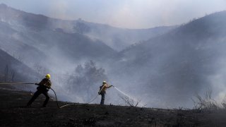Firefighters put out hotspots from the Elsmere fire, fueled by hot and dry temperatures Monday, Aug. 3, 2020, in Santa Clarita, Calif. (AP Photo/Marcio Jose Sanchez)