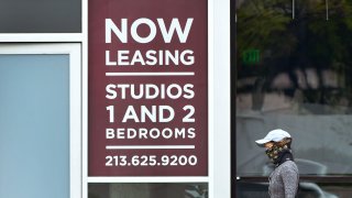 A woman wrapped in facial covering walks past apartments for rent.