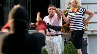 In this June 28, 2020, file photo, armed homeowners Mark T. and Patricia N. McCloskey stand in front their house along Portland Place as they confront protesters marching to St. Louis Mayor Lyda Krewson's house in the Central West End of St. Louis.