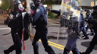 Federal officers use riot shields to push a protester while dispersing a crowd of about 150 people from in front of the Immigration and Customs Enforcement (ICE) detention facility on August 20, 2020 in Portland, Oregon.
