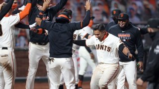 Donovan Solano #7 of the San Francisco Giants is congratulated by teammates after he hit a walk off home run to win the game in the 11th inning against the Los Angeles Dodgers at Oracle Park on August 25, 2020 in San Francisco, California. (Photo by Ezra Shaw/Getty Images)