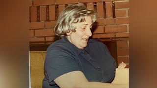Woman with a blue shirt sits looking down