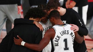 In this July 31, 2020, file photo, San Antonio Spurs guard Lonnie Walker IV (1) has Black Lives Matters on the back of his jersey in a huddle before an NBA basketball game against the Sacramento Kings in Lake Buena Vista, Fla.