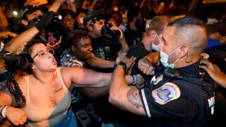 Metropolitan Police are confronted by protestors as police carry away a handcuffed protestor along a section of 16th Street, Northwest, renamed Black Lives Matter Plaza, Thursday night , Aug. 27, 2020, in Washington, after President Donald Trump had finished delivering his acceptance speech from the White House South Lawn.