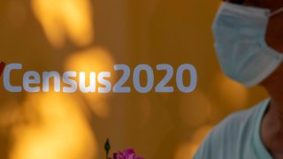 A man wearing a facemask walks past a sign encouraging people to complete the 2020 US Census, in Los Angeles, California, August 10, 2020 amid the COVID-19 pandemic.