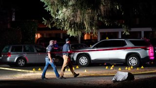 Police walk past evidence markers at a scene in Lacey, Washington