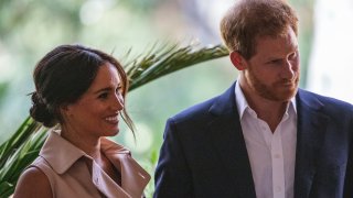 Britain's Prince Harry, Duke of Sussex(R) and Meghan, the Duchess of Sussex(L) stand on the stage at the British High Commissioner residency in Johannesburg where they will meet with Graca Machel, widow of former South African president Nelson Mandela, in Johannesburg, on October 2, 2019. - Prince Harry recalled the hounding of his late mother Diana to denounce media treatment of his wife Meghan Markle, as the couple launched legal action against a British tabloid for invasion of privacy.
