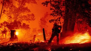 In this Sept. 7, 2020, file photo, a firefighter works the line as flames push towards homes during the Creek fire in the Cascadel Woods area of unincorporated Madera County, California.