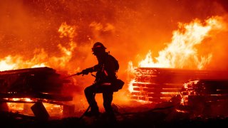 A firefighter douses flames as they push towards homes during the Creek fire in the Cascadel Woods area of unincorporated Madera County, California on September 7, 2020.