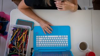 A mother working from home sits alongside her son, not pictured, attending school remotely in an arranged photograph taken in Miami, on Tuesday, Sept. 8, 2020.