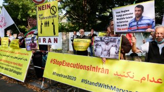 In this Sept. 12, 2020, photo, demonstrators are holding banners in front of the Iranian Embassy in Berlin to protest against the execution of the wrestler Navid Afkari