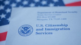 Hand touching Letter (Envelope) from USCIS on flag of USA background. Close up view.