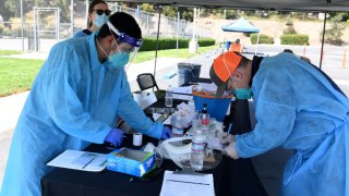 File Image: Mend Urgent Care workers wearing personal protective equipment perform drive-up COVID-19 testing for students and faculty on the first day of school at Woodbury University on August 24, 2020 in Burbank, California.
