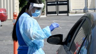 Mend Urgent Care workers wearing personal protective equipment perform drive-up COVID-19 testing for students and faculty at University Prep Value High School on September 18, 2020 in Los Angeles, California. Most California schools have gone virtual while others are placing physical distancing and other protocols like testing to keep in-person classes in session.
