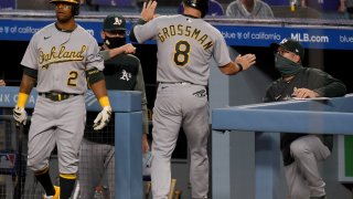 Robbie Grossman #8 of the Oakland Athletics celebrates his run with Khris Davis #2, and Bob Melvin #6, from a sacrifice fly from Mark Canha #20, to take a 2-0 lead over the Los Angeles Dodgers, during the first inning at Dodger Stadium on September 23, 2020 in Los Angeles, California. (Photo by Harry How/Getty Images)
