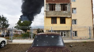 Shrapnel holes in a car as a building burns in the background after shelling by Azerbaijan’s artillery during a military conflict in self-proclaimed Republic of Nagorno-Karabakh, Stepanakert, Azerbaijan, Sunday, Oct. 4, 2020. The fighting between Armenian and Azerbaijani forces has continued on Sunday over the separatist territory of Nagorno-Karabakh, with Azerbaijan’s second largest city, Ganja, coming under attack.