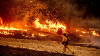 A firefighter passes flames while battling the Glass Fire in a Calistoga, Calif., vineyard Thursday, Oct. 1, 2020.