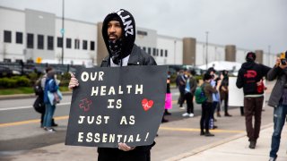 Chris Smalls, a fired Amazon fulfillment center employee, center, holds a sign during a protest outside an Amazon.com facility in the Staten Island borough of New York, U.S., on Friday, May 1, 2020. Workers at Amazon, Whole Foods, Instacart, Walmart, FedEx, Target, and Shipt said they would walk off the job to protest their employers’ failure to provide basic protections for employees who are risking their lives at work. Photographer: Michael Nagle/Bloomberg via Getty Images