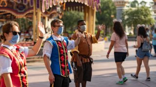 In this July 11, 2020, file photo provided by Walt Disney World Resort, Disney cast members welcome guests to Magic Kingdom Park at Walt Disney World Resort in Lake Buena Vista, Florida.