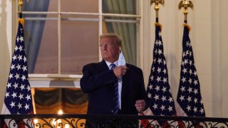 President Donald Trump takes off his face mask as he arrives at the White House upon his return from Walter Reed Medical Center, where he underwent treatment for Covid-19, in Washington, D.C, on Oct. 5, 2020.