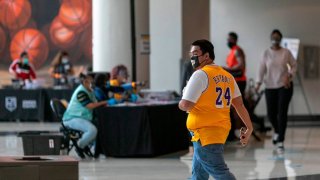 A man wears a jersey honoring the late Lakers basketball star, Kobe Bryant, at the Vote Center at Staples Center sports and entertainment arena on the first day of early voting in Los Angeles, California, on October 24, 2020. – Voters can drop off mail-in ballots or vote in person from October 24 through November 3. (Photo by DAVID MCNEW / AFP) (Photo by DAVID MCNEW/AFP via Getty Images)