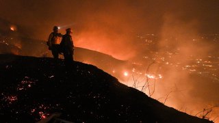 Firefighters look out over a burning hillside as they fight the Blue Ridge Fire in Yorba Linda, California.