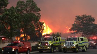 Firetrucks stage on Elinvar Drive in Chino Hills as the Blue Ridge Fire burns in Chino Hills State Park near homes.