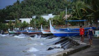 Residents walk past parked wooden boats along a boulevard in Legaspi, Albay province, south of Manila on October 31, 2020, ahead of Typhoon Goni's landfall.